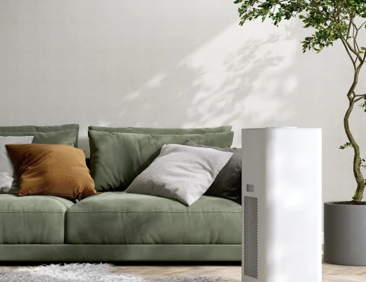 Moderner weißer Luftentfeuchter im Wohnzimmer neben grünem Sofa zur Regulierung der Luftfeuchtigkeit