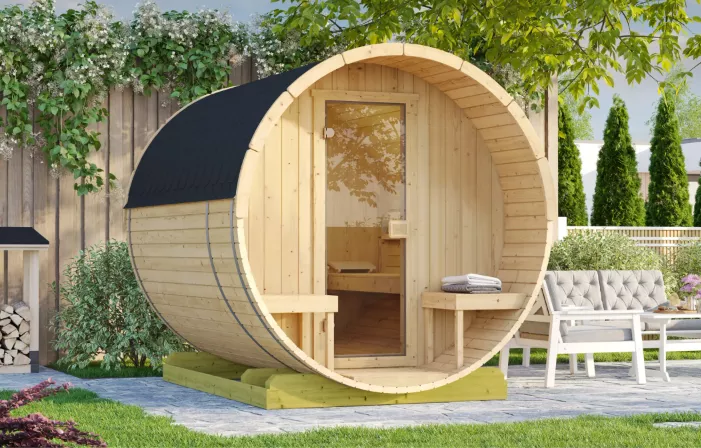 Fasssauna aus Holz im Garten mit Sitzbereich davor