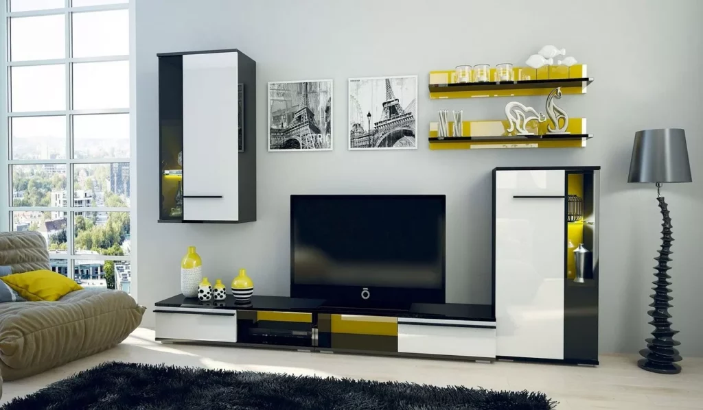 Hochglanzmöbel Trends 2025 – moderne Wohnwand im Wohnzimmer in Schwarz-Weiß mit gelben Akzenten, TV-Board, Hängeschränken und Deko.