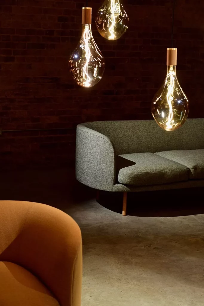 Modern eingerichtetes Wohnzimmer mit schlichten Sofas und großen, hängenden Glühbirnen – Beispiel für minimalistisches Interior Design.