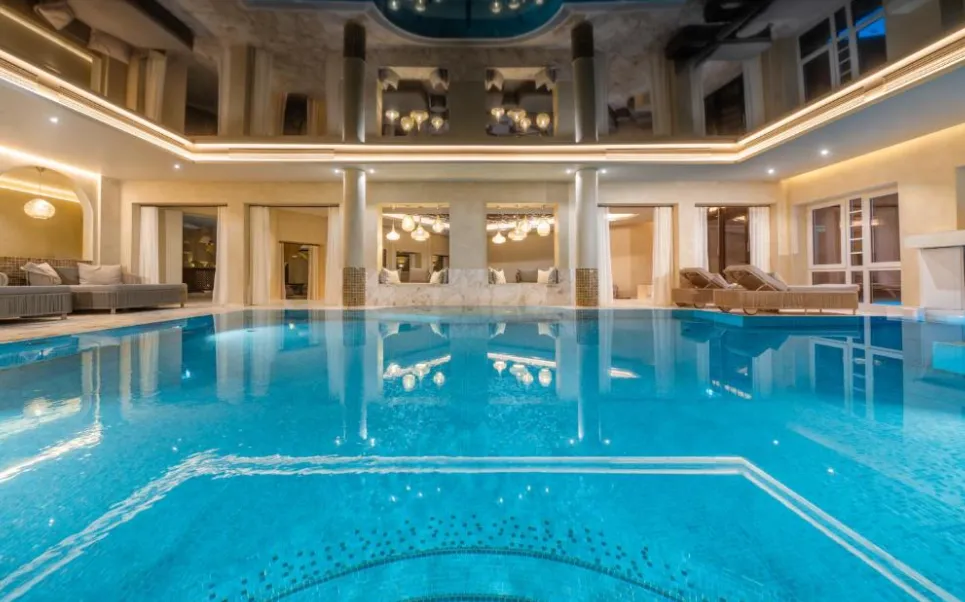 Beheizter Indoor-Infinity-Pool im Vitalhotel Alter Meierhof mit Lounge-Bereichen und warmem Ambientelicht