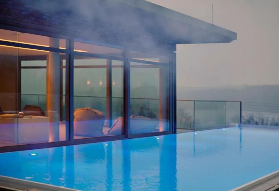 Beheizter Rooftop-Infinity-Pool im Hotel Seegarten bei Abenddämmerung mit Dampf und Glasbrüstung