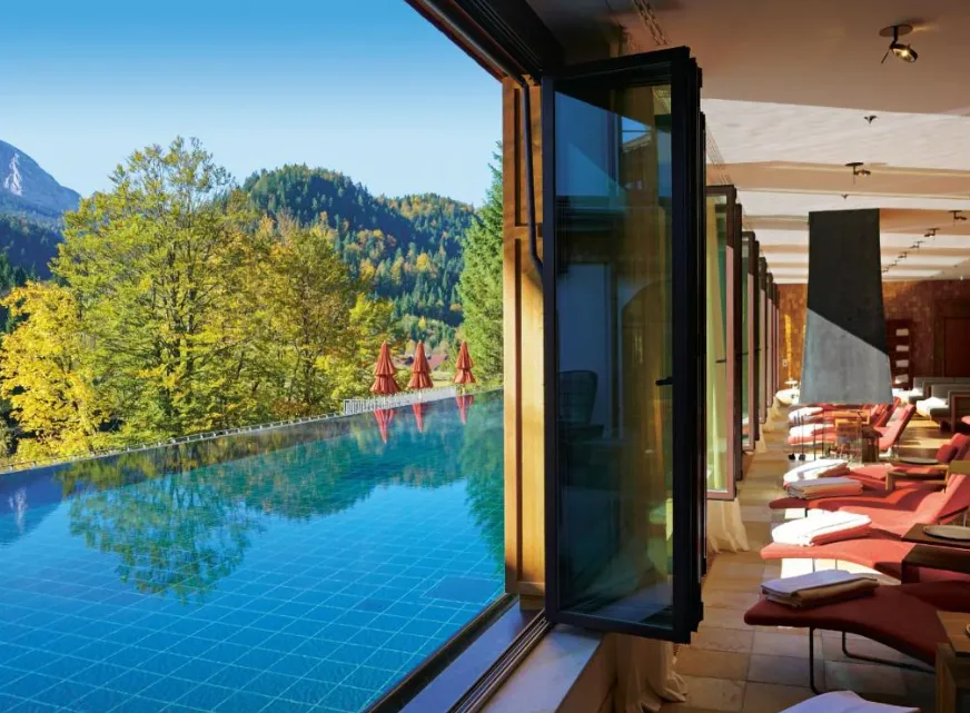 Infinity-Pool im Schloss Elmau mit Blick auf die bayerischen Alpen und herbstlichen Wald