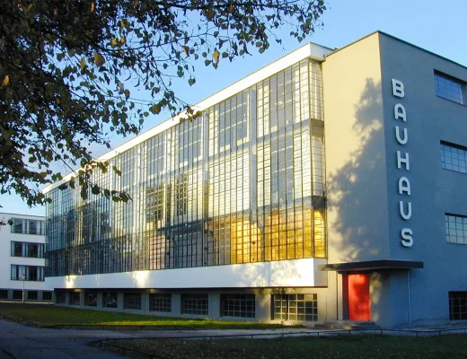 Bauhaus Stil Architektur: Bauhausgebäude in Dessau mit Glasvorhangfassade, klaren Kuben und roter Eingangstür im Abendlicht