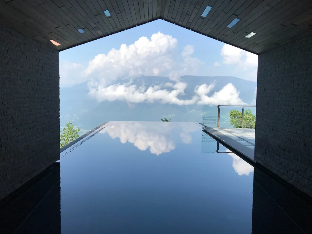 Infinity-Pool in den Bergen mit Spiegelung von Wolken, gerahmt von moderner Architektur