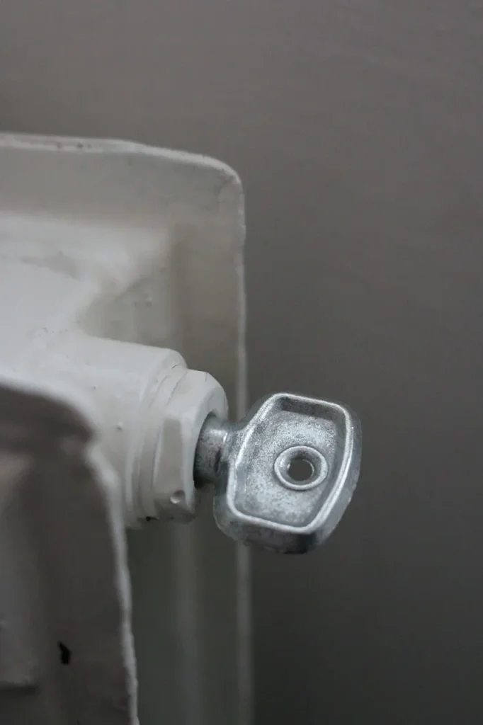 „Entlüftungsventil eines Heizkörpers mit eingesetztem Entlüftungsschlüssel – Vorbereitung zum Heizung entlüften.