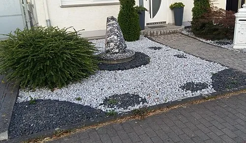 Ein Schottergarten mit weißen Kiesflächen und dunklem Splitt