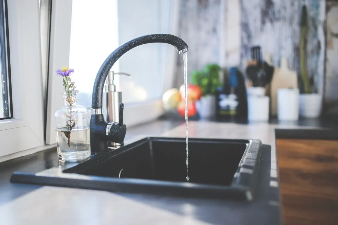 Laufender Wasserhahn in einer Küche – Trinkwasserhygiene im Sommer