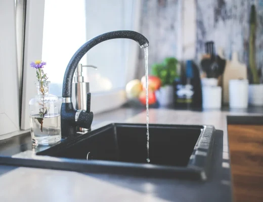 Laufender Wasserhahn in einer Küche – Trinkwasserhygiene im Sommer